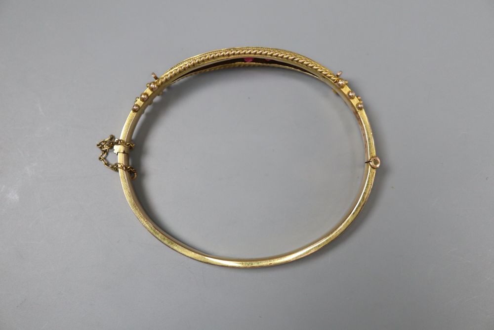 A cased Edwardian 9ct gold and graduated red stone doublet set hinged bracelet,